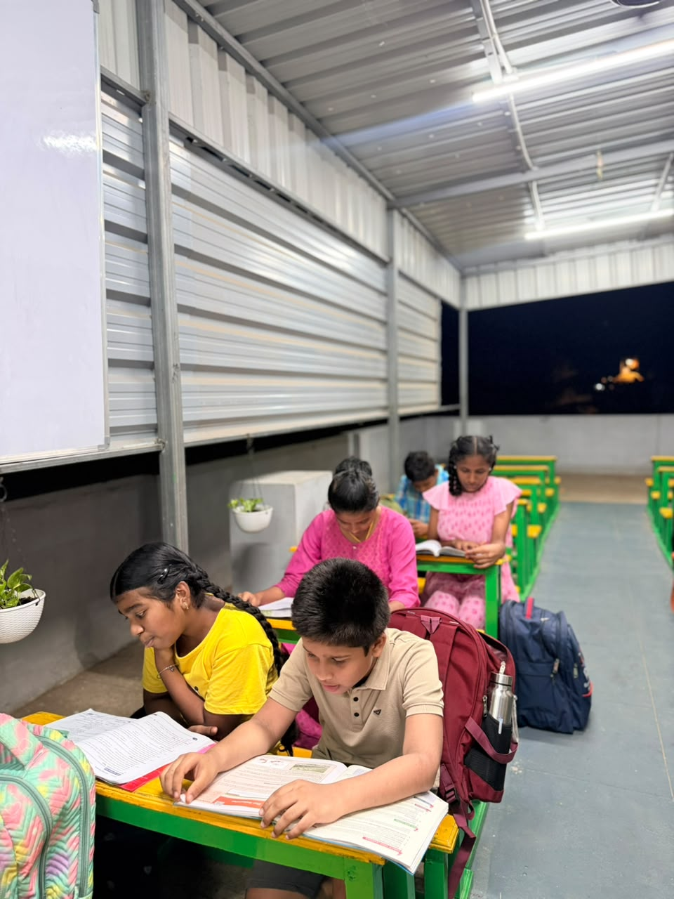 Students at D Academy practising written work under the classroom lights