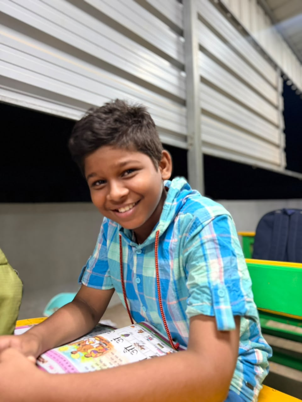 A smiling D Academy student at his desk with a practice workbook